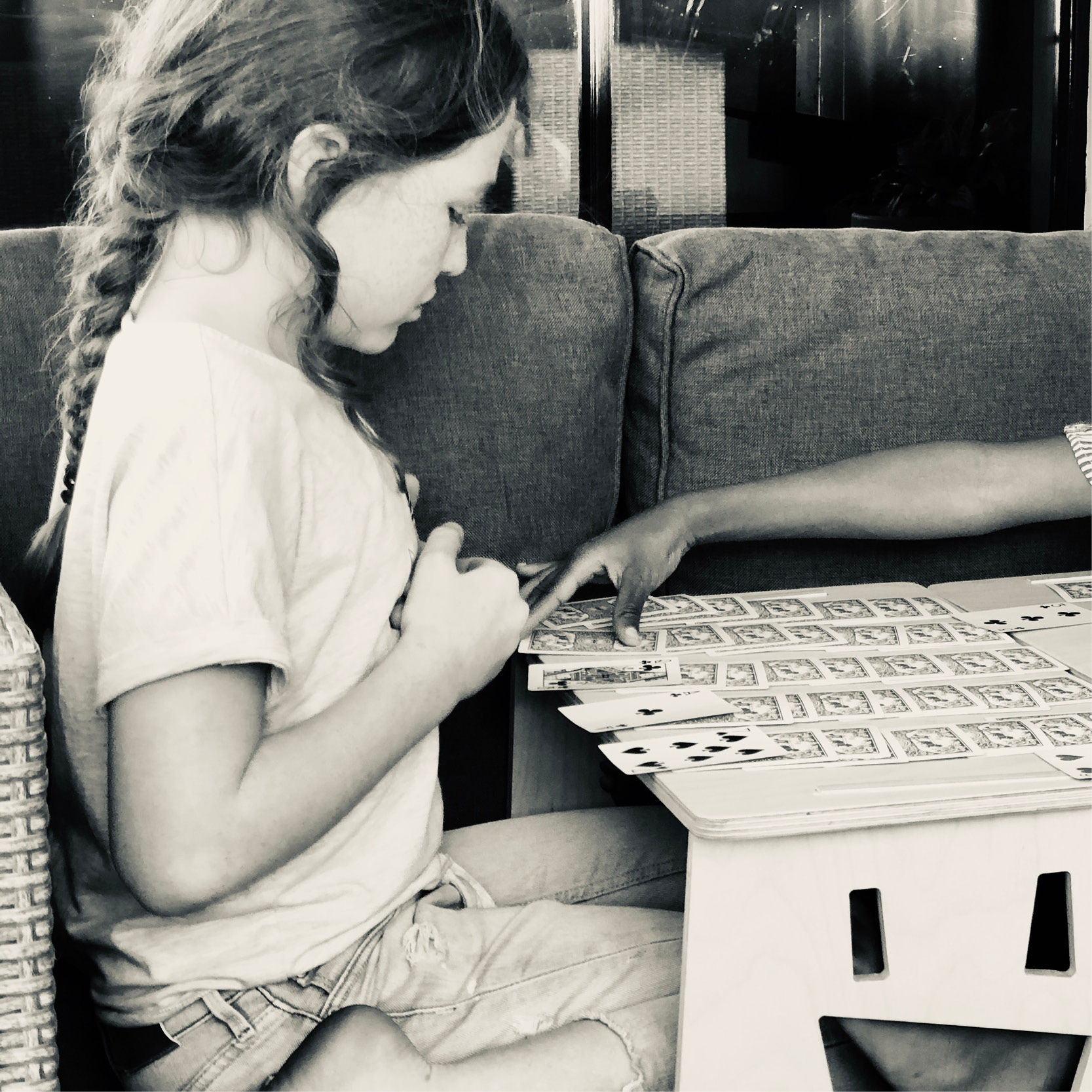 Black and white photo of a child playing cards on a MyDinky step