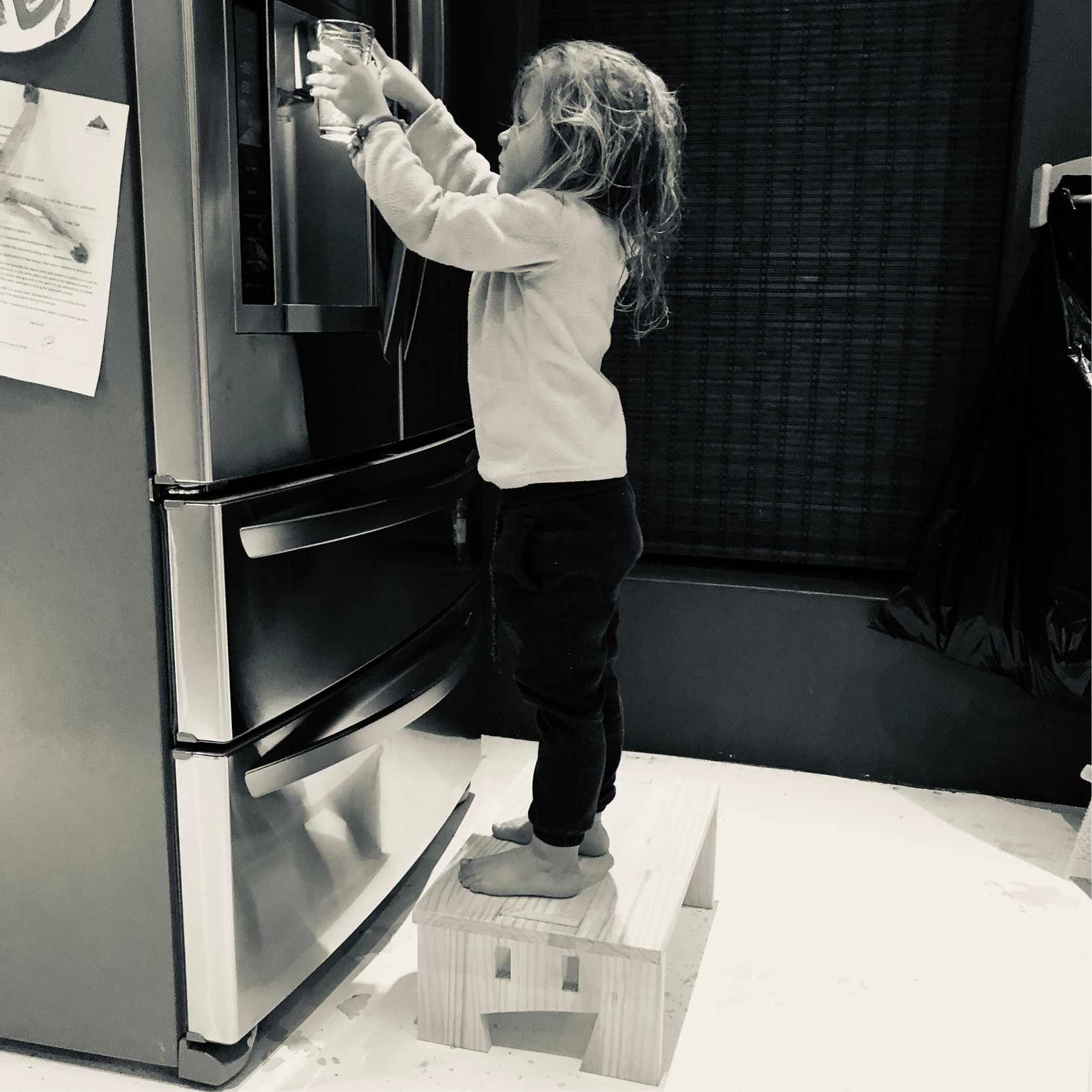 Black and white photo of child using MyDinky step to reach water